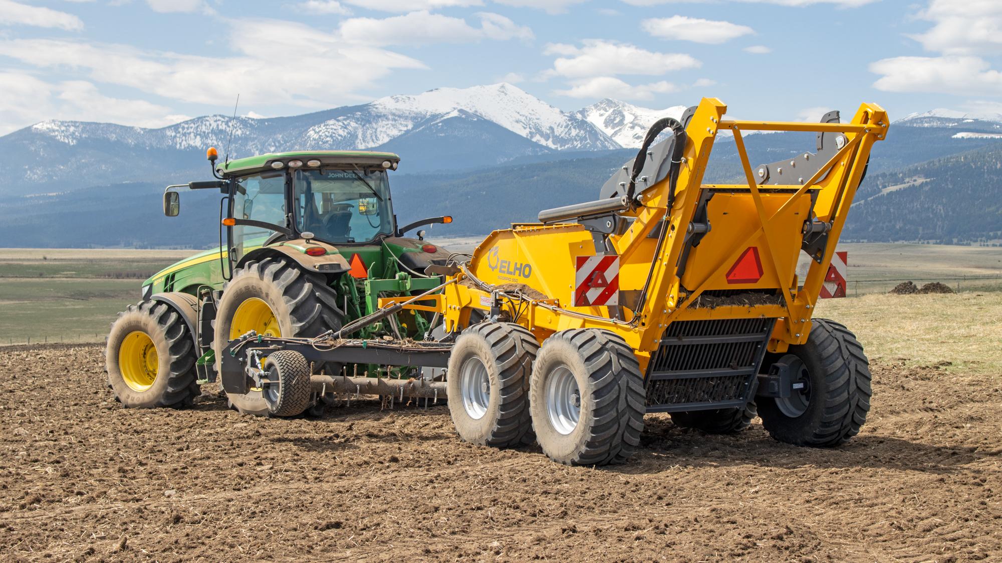 Tractor pulling a rock picker through a field